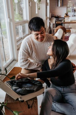 A cozy indoor scene showing two people opening a package by sunny windows.