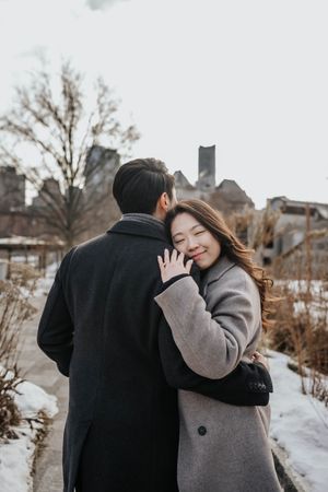 A couple shares tender moments in a snowy winter setting while wearing warm coats.