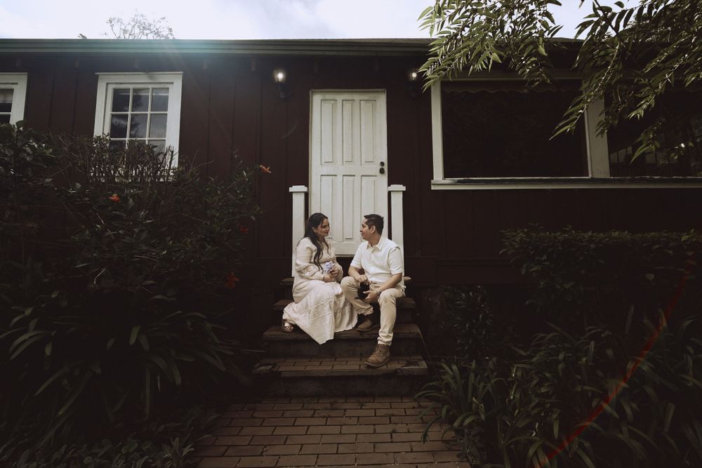 Family sits together on white porch steps of dark house.