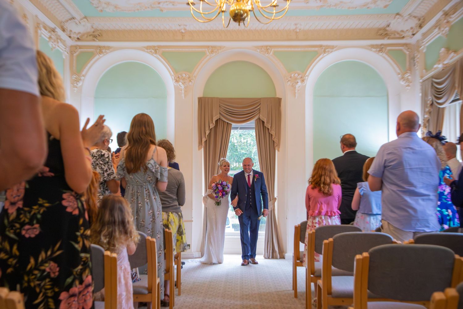 Bride and groom walking down aisle at Follaton House, Devon