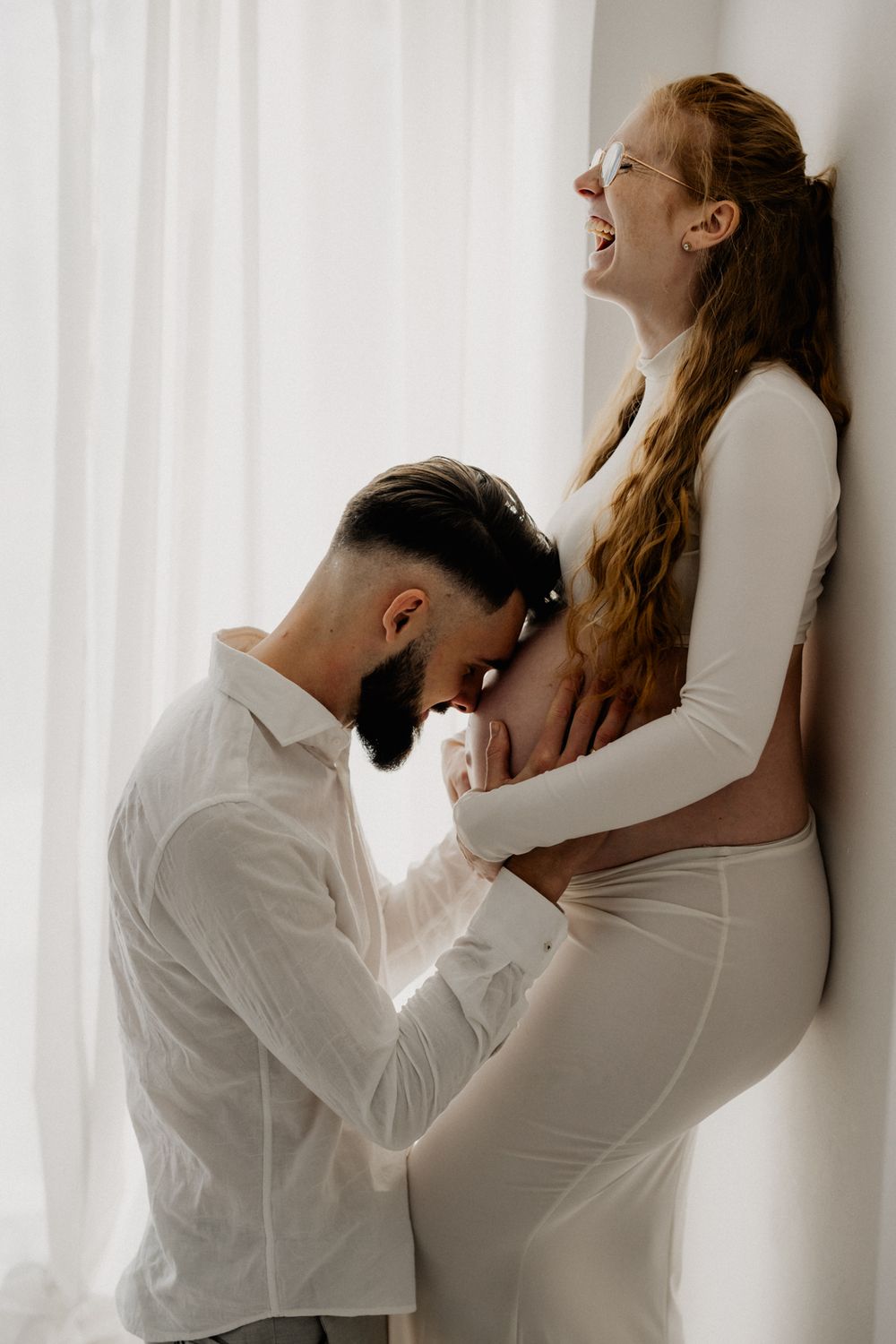 A couple in white clothing poses intimately against a wall in a series of romantic artistic photographs.
