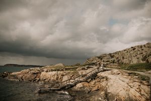 Dramatic coastal landscape with rugged cliffs and stormy skies over the rocky shoreline at dusk.