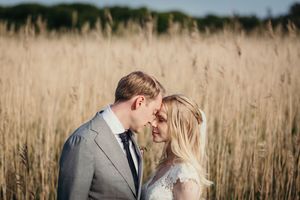 A couple shares a romantic moment together in a golden wheat field at sunset.