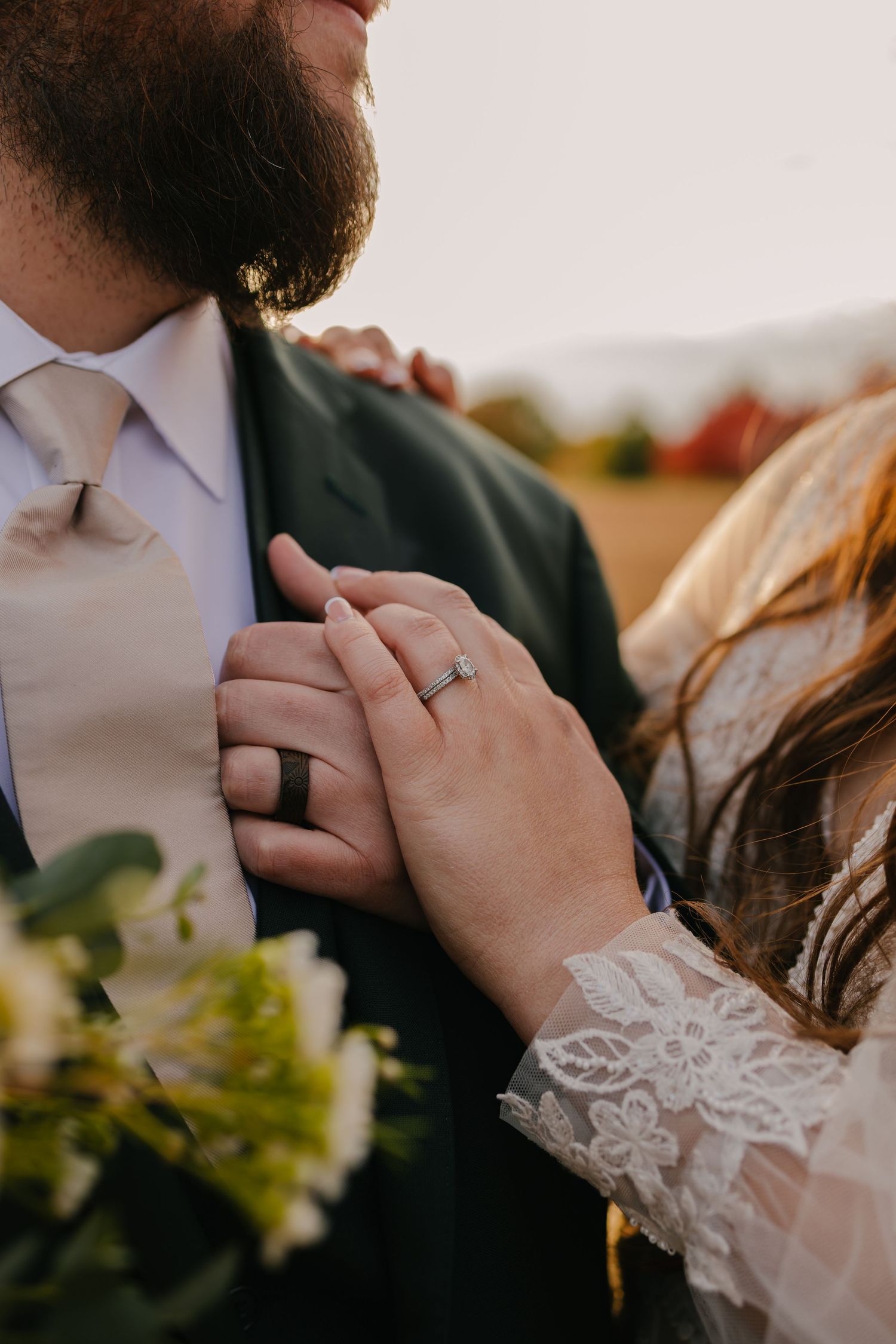 Close-up of hands holding a wedding bouquet with magnolia leaves and greenery.
