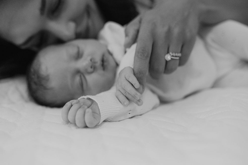 A black and white close-up of tiny baby hands being held with gentle care.