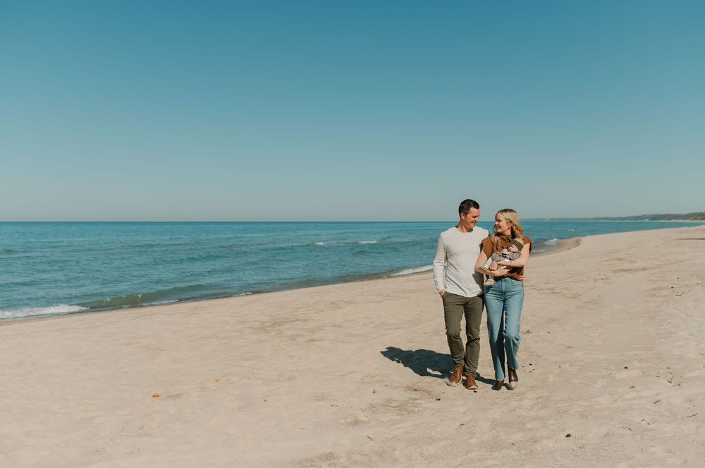 Two people walk together on a peaceful beach shoreline on a clear sunny day.