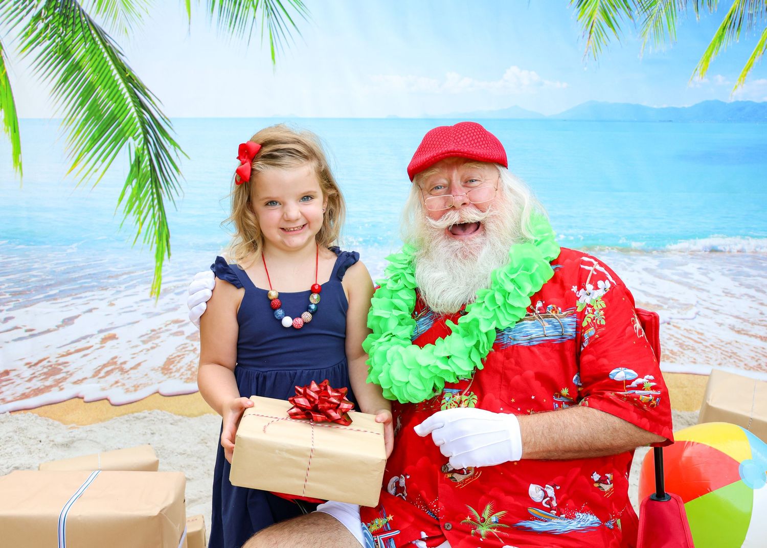 A tropical-themed holiday photo with presents and palm tree decorations.