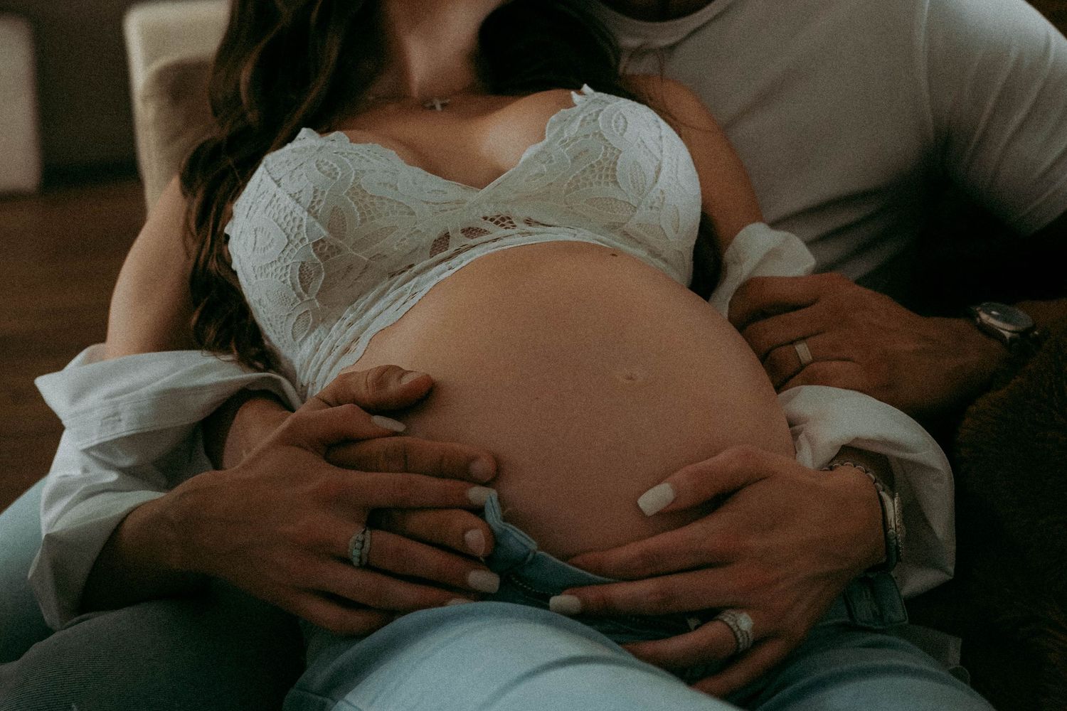 Close up of Palm Beach pregnant belly being tenderly held by hands in romantic lighting.