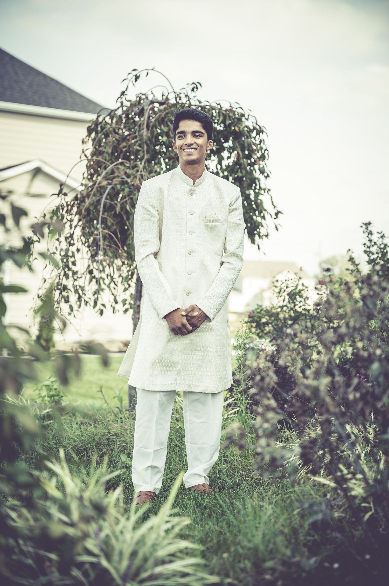 Garden setting with white formal attire photographed among lush greenery and purple flowers.