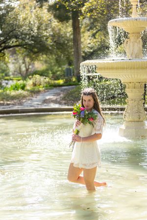 A series of whimsical photos showing someone playing and splashing in a sunlit fountain with colorful flowers.