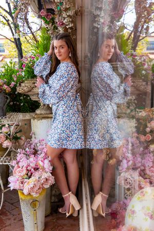 A floral spring scene with pink cherry blossoms and someone wearing a blue floral dress and beige heels.