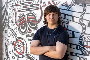 Students posed against a wall decorated with black and red tribal-style artwork and patterns.