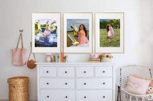 A white dresser with three framed photos above it and hanging bags, creating a cozy bedroom corner display.