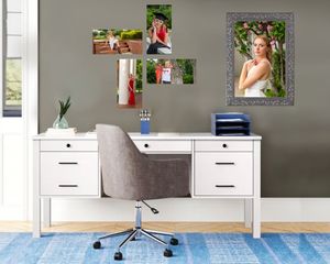 Modern gray office chair with ergonomic design and white desk against neutral wall with framed photos.