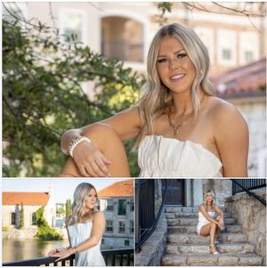 Bride in a strapless white wedding dress poses outdoors against stone walls and greenery in a romantic setting.