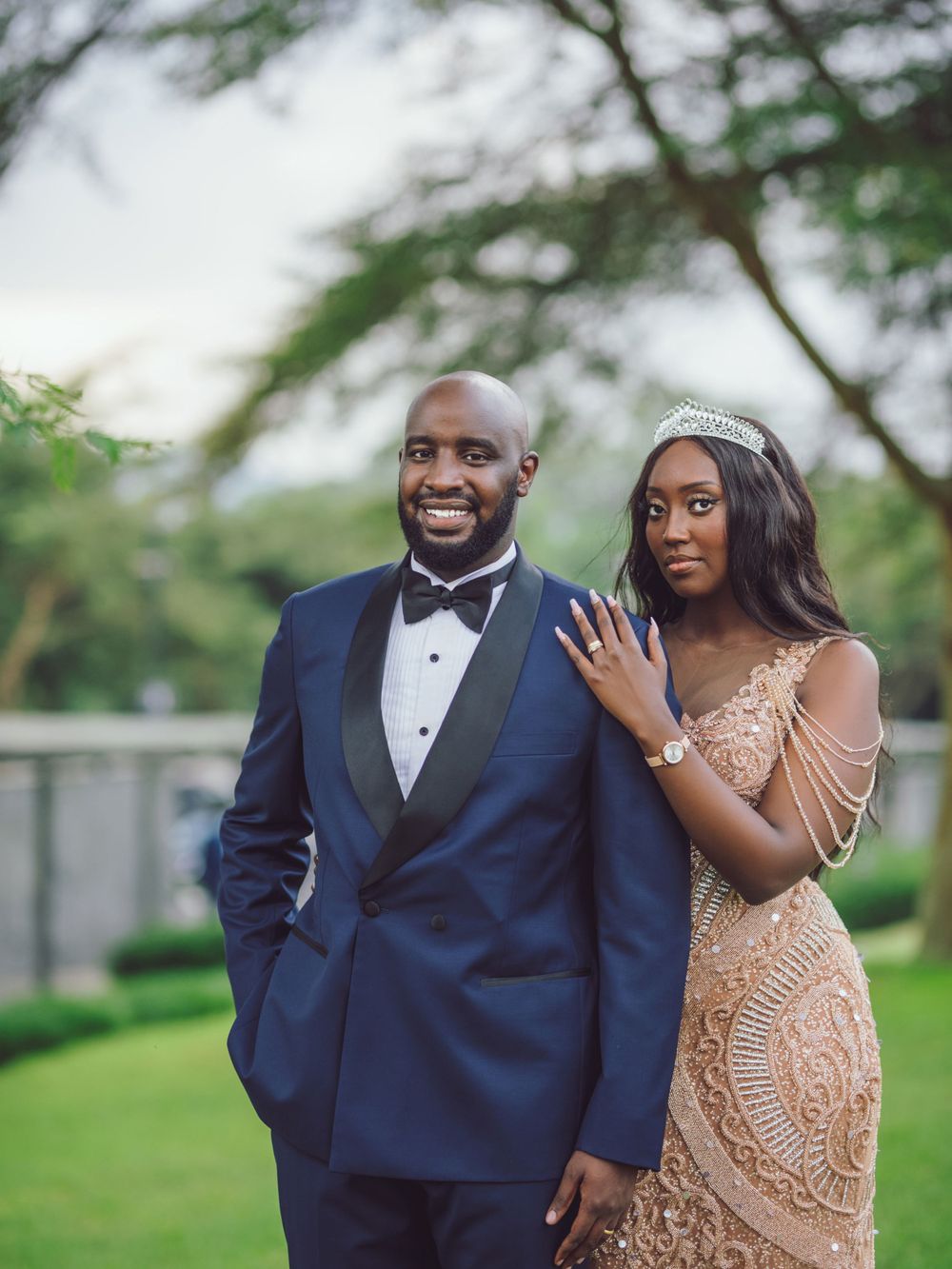 Couple poses in formal attire against lush garden backdrop for wedding photos.