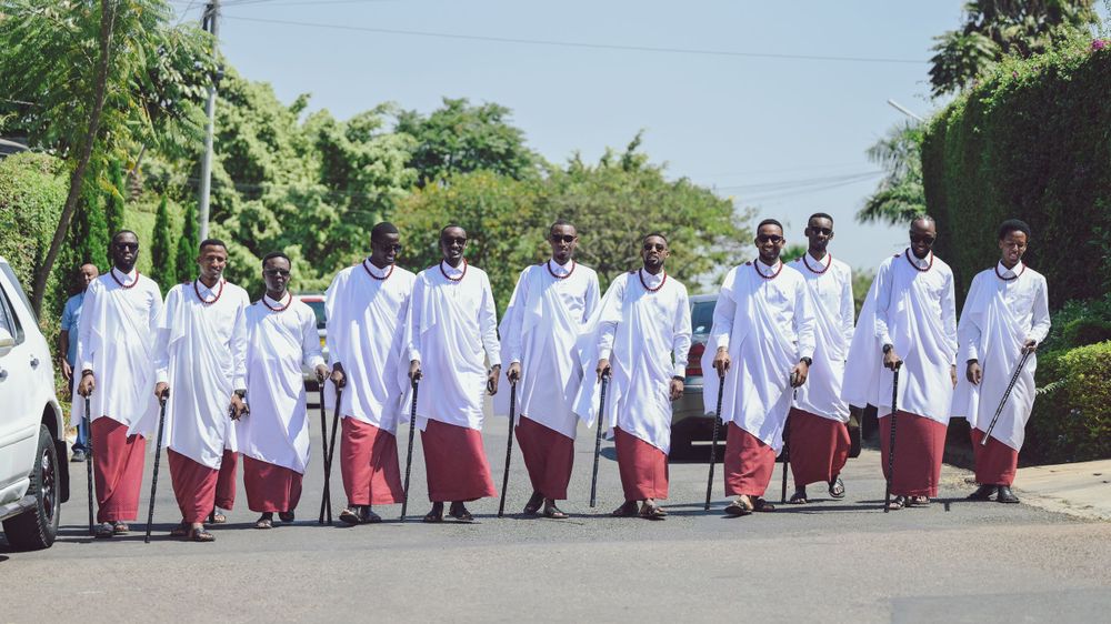 Group of choir members wearing white robes and red stoles walking in formation.