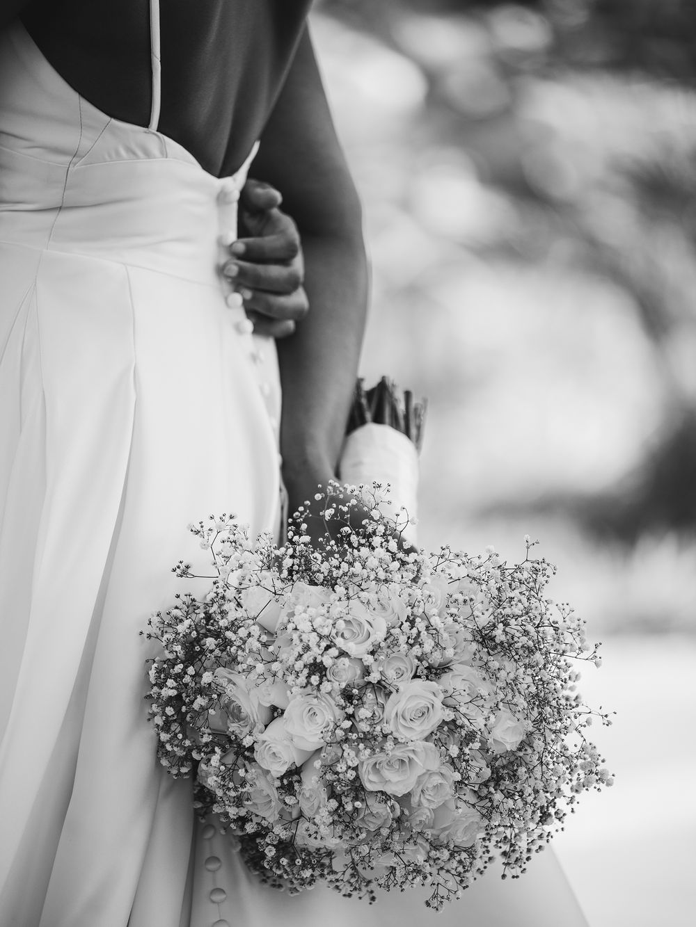 Black and white close-up of a delicate wedding bouquet with baby's breath and white flowers.