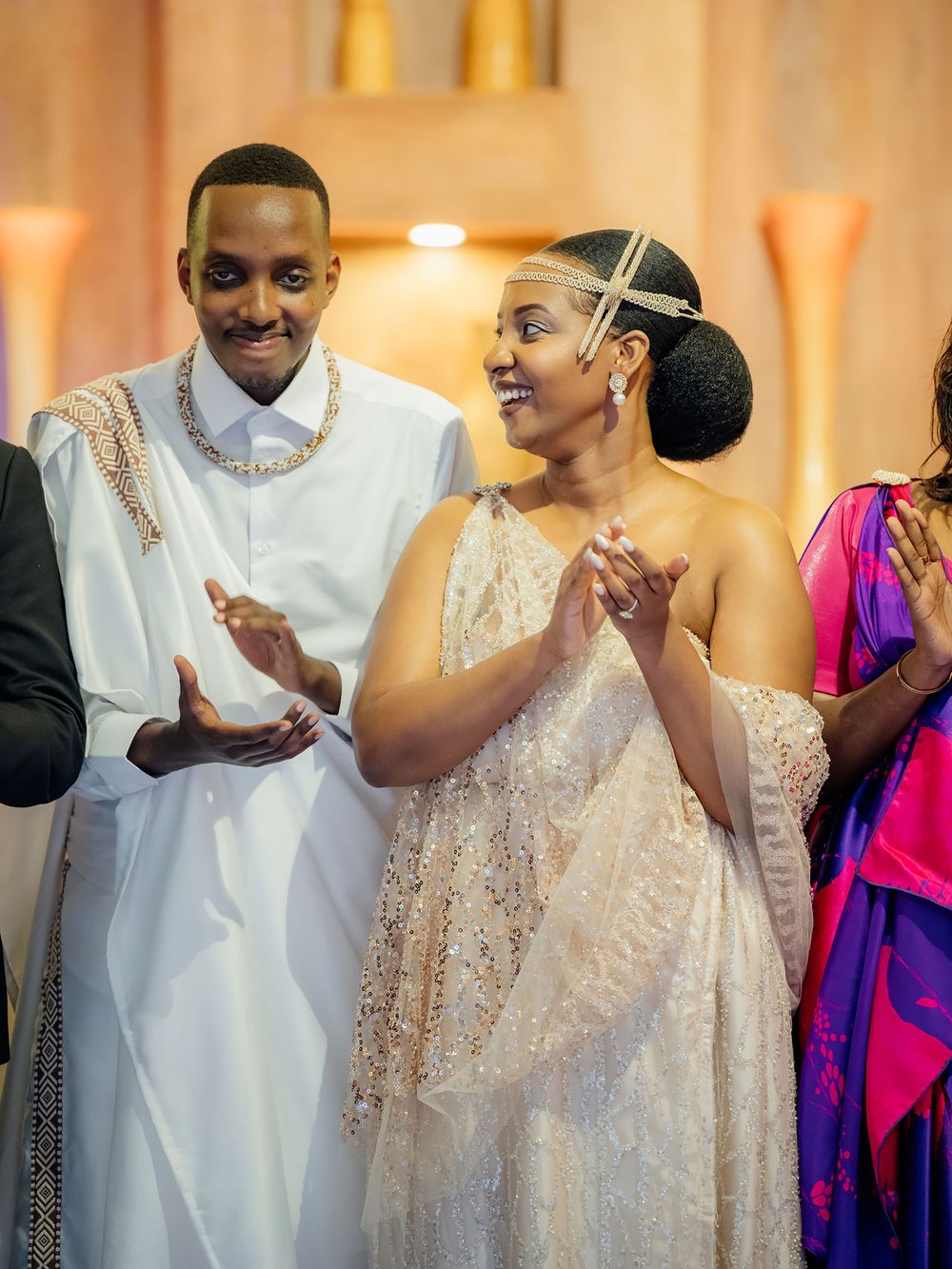 Joyful celebration at an elegant wedding with attendees wearing formal white and pink attire.