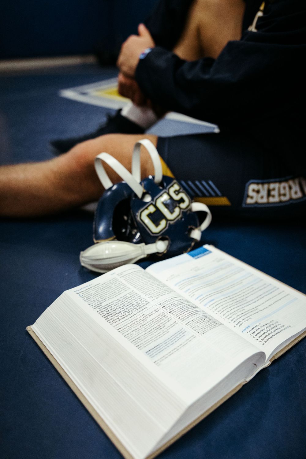 An open textbook with CU athletic gear in the background showing a study session on a blue surface.