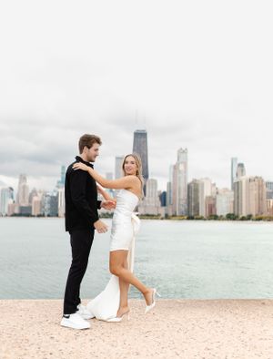 A couple dances together on the beach with the Chicago skyline in the background.