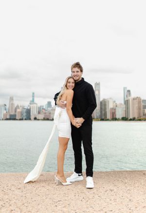 A couple shares a tender moment on North Avenue Beach with Chicago's skyline as backdrop.