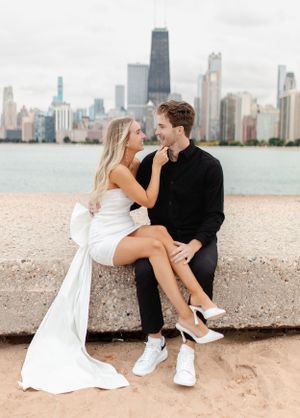 Couple sharing a romantic moment on concrete barrier with Chicago skyline in view.