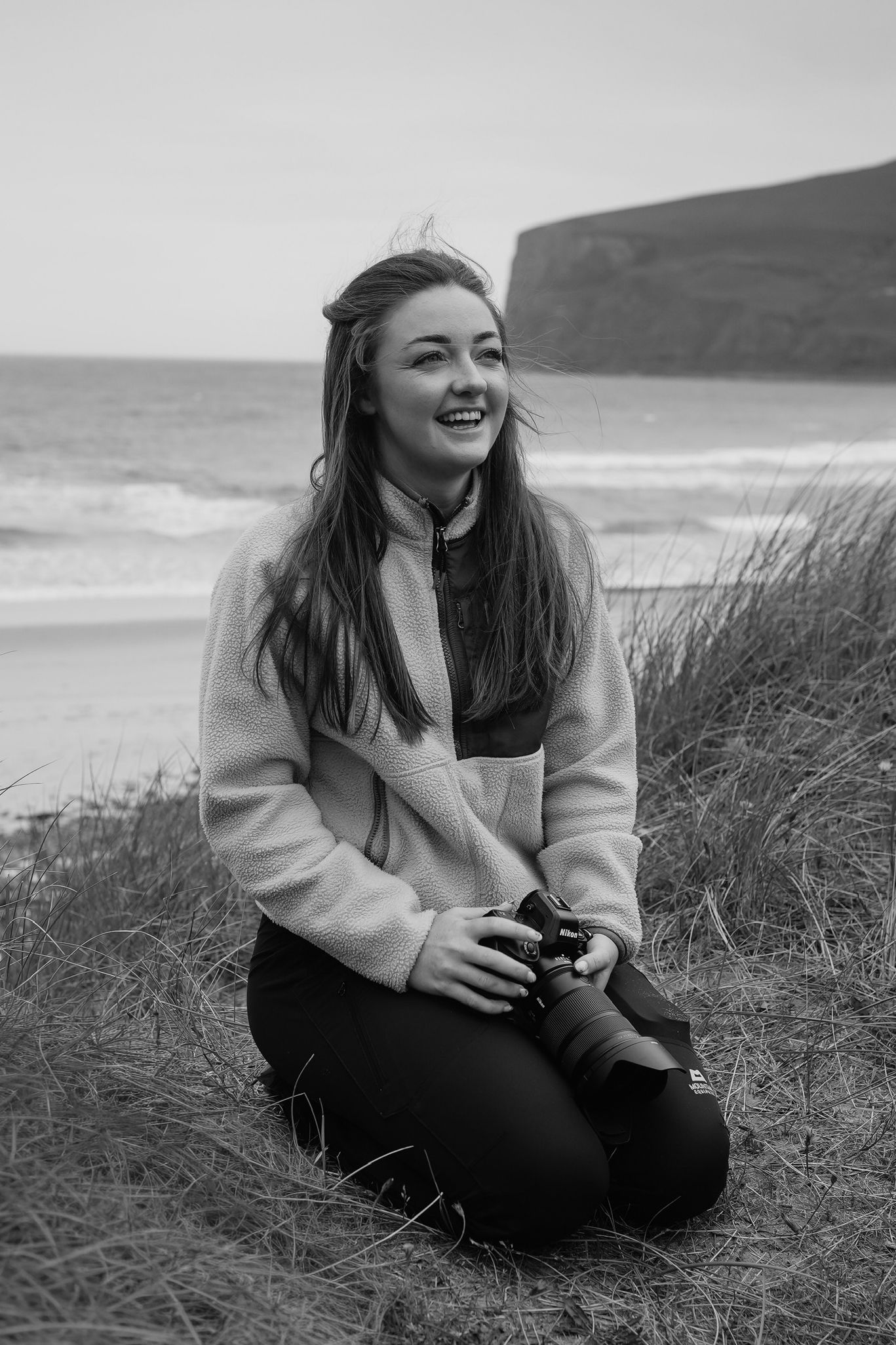 A black and white photograph showing someone smiling while wearing a North Face winter jacket outdoors.
