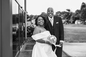 Joyful Black bride and groom smiling together in black and white outdoor wedding portrait.