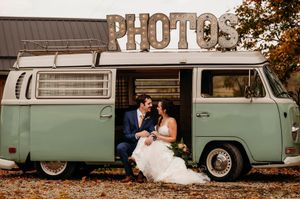 Newlyweds sitting inside a vintage mint green VW bus photo booth at their wedding celebration.