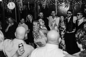 Wedding guests dancing and celebrating together at a lively indoor reception party.