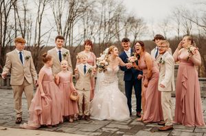 Wedding party in dusty rose and navy attire celebrates outdoors with bride and groom on stone patio.
