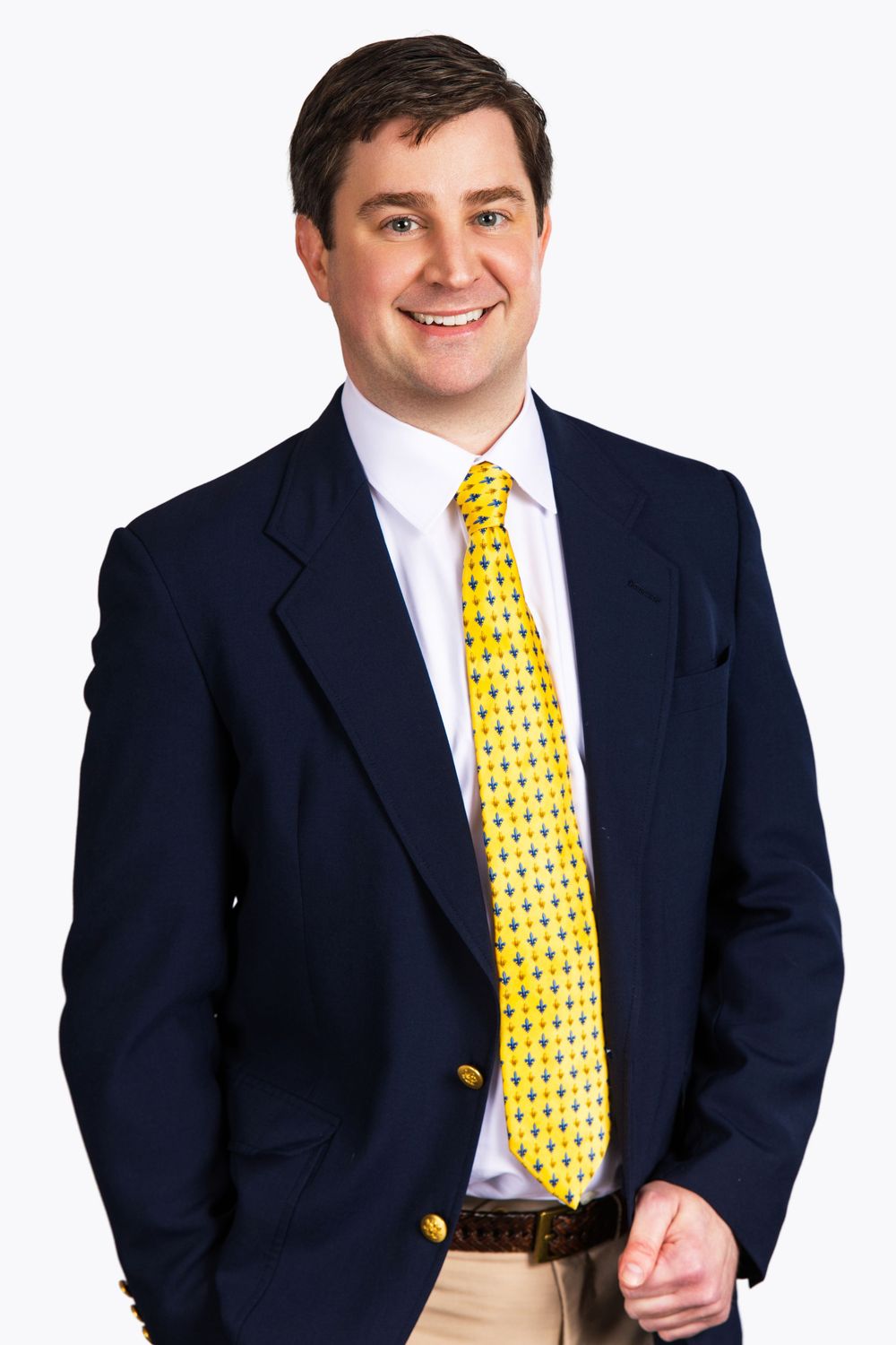 Professional man in navy blazer and yellow tie smiles confidently in business portrait photo.