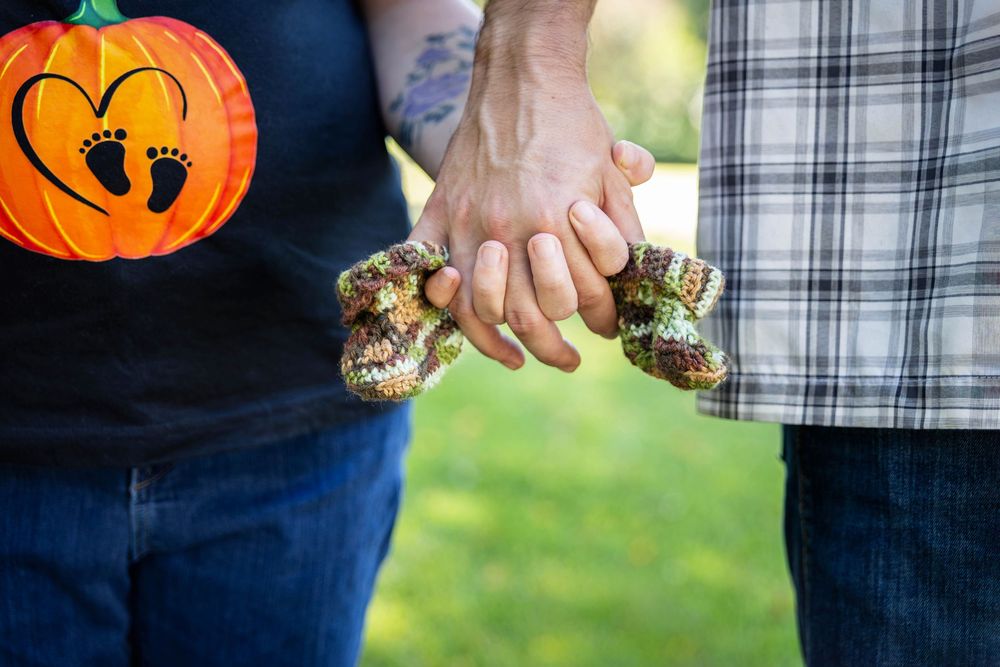 A couples hands close up holding onto baby booties.