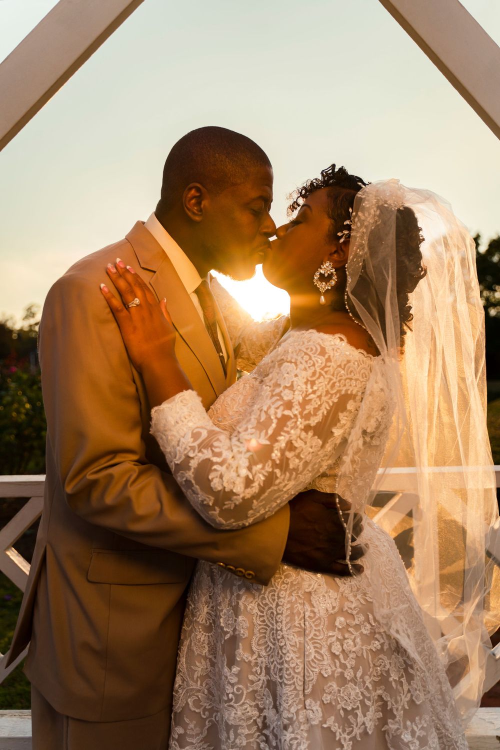 A romantic sunset wedding portrait captures a tender kiss between newlyweds on their special day.