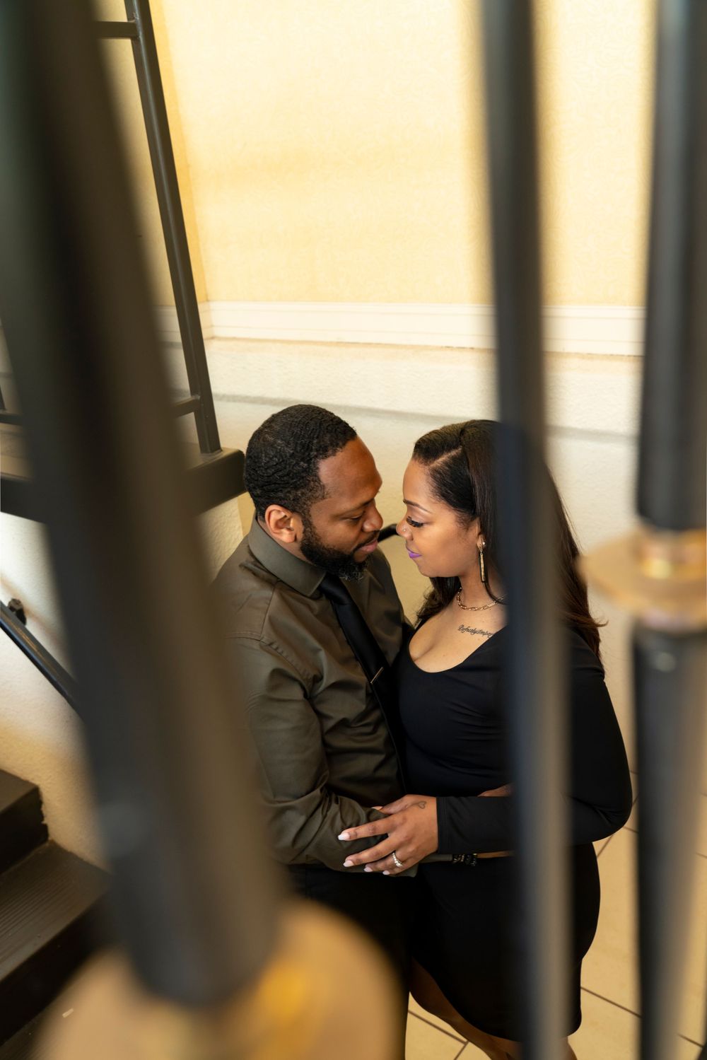 An intimate moment between a couple framed through architectural elements in warm lighting.