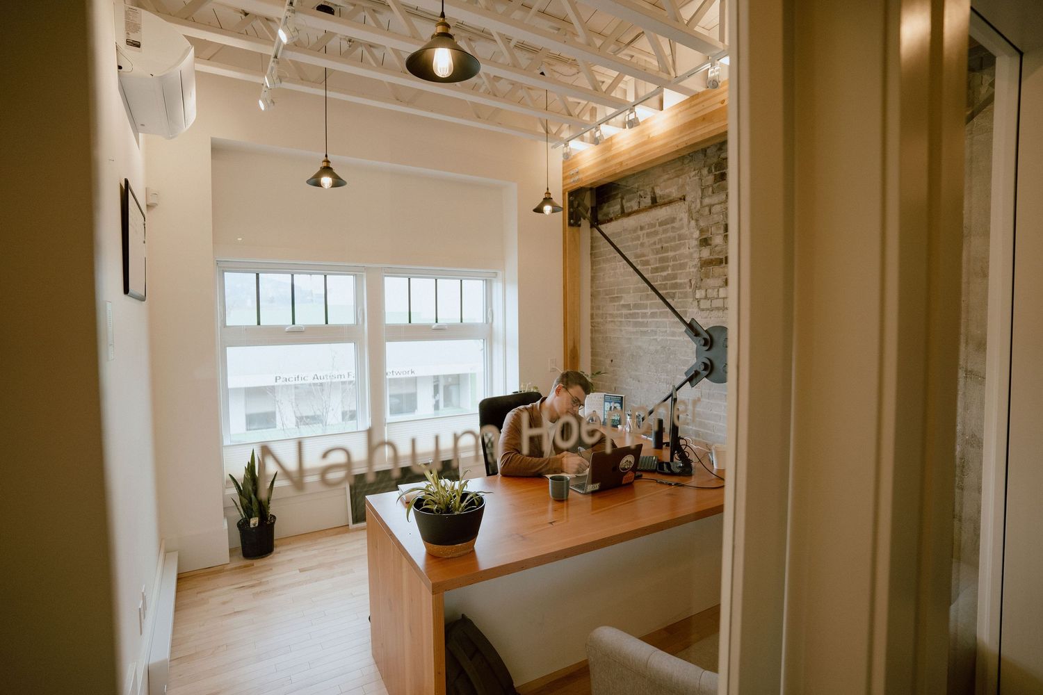 Bright modern kitchen space with wooden countertop and large windows letting in natural light.