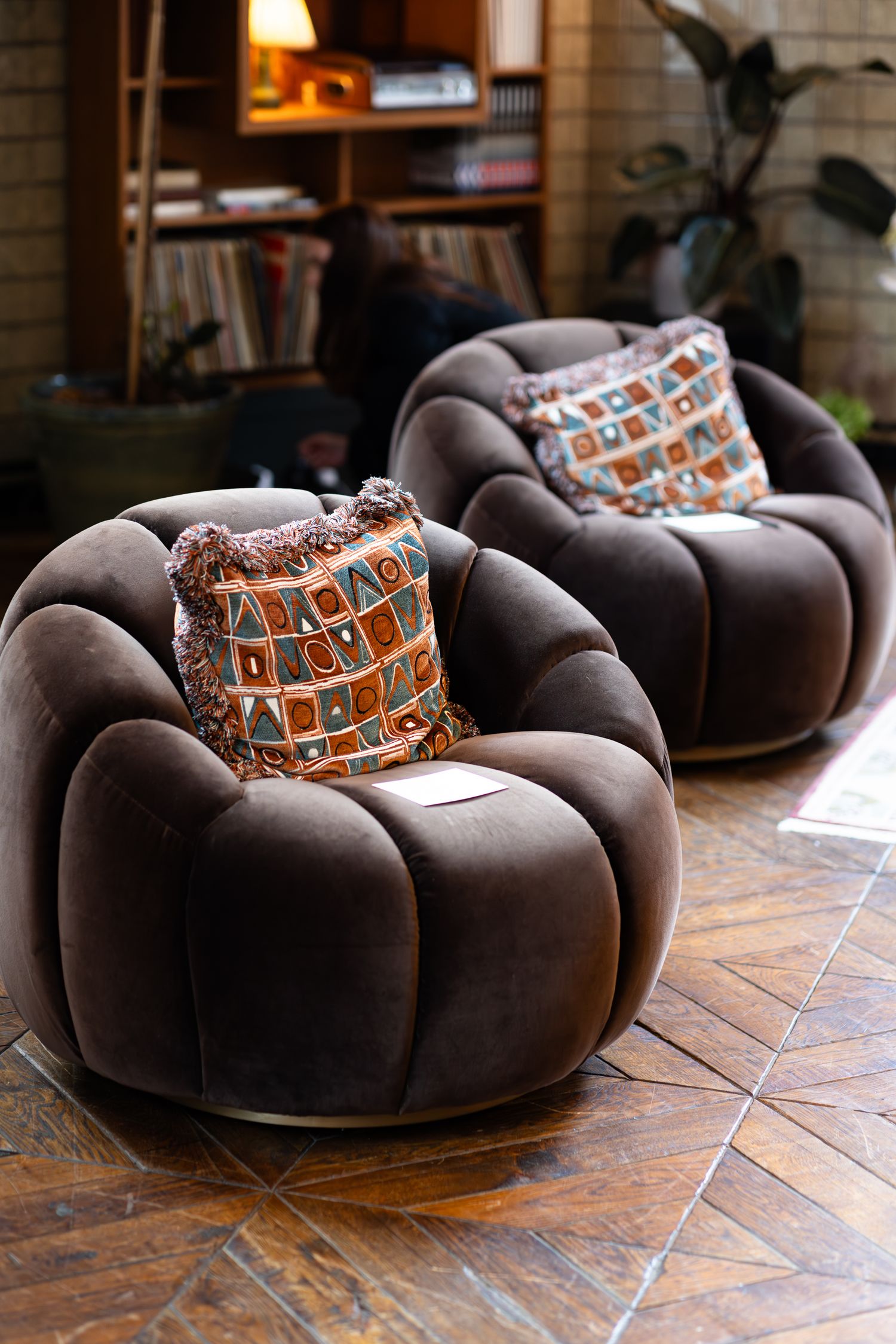 Brown plush circular lounge chairs with patterned cushions on wooden flooring.