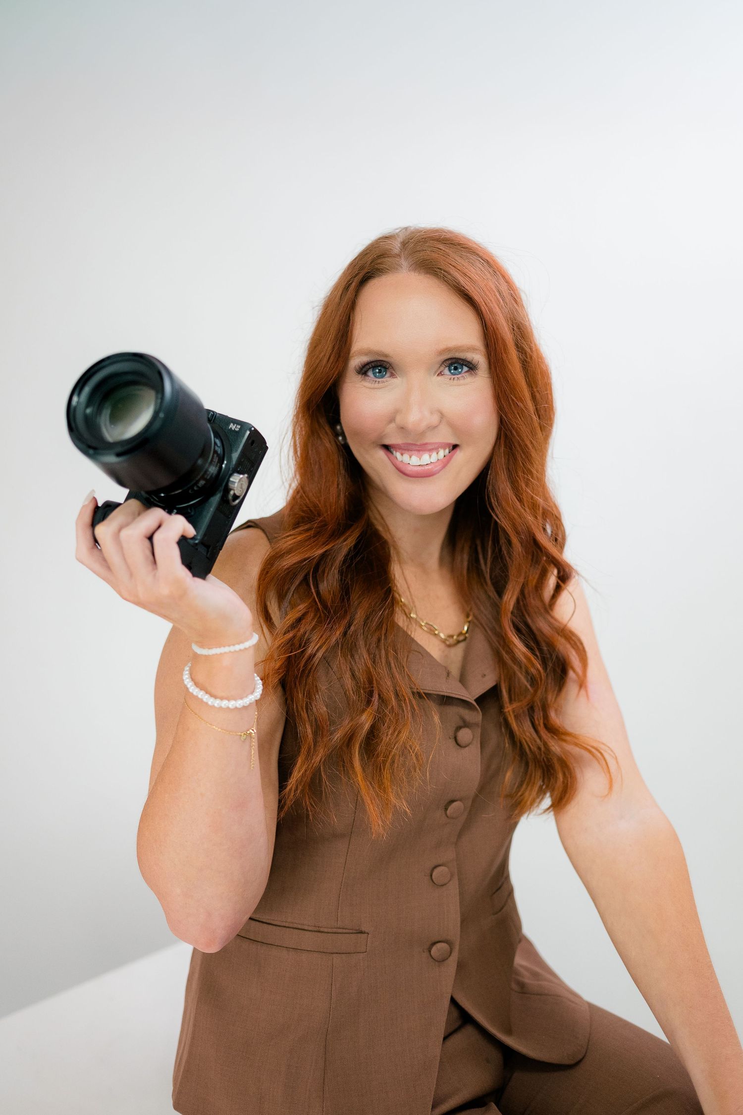 Lifestyle portrait of photographer showing vintage camera while wearing white hat.