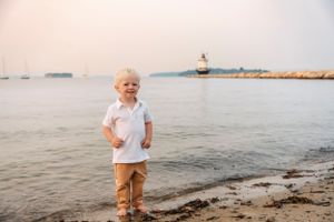 Child walking along rocky beach coastline at sunset.