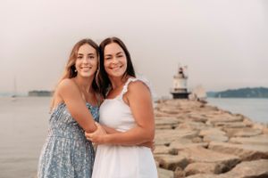 Two people embracing on rocky coastal shoreline at dusk.