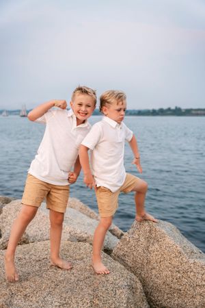 Children playing together on large coastal rocks by the ocean.