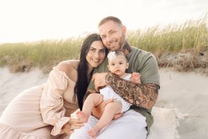 Family portrait on beach with tall grass at sunset.