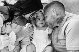Black and white intimate family portrait with baby in white dress.