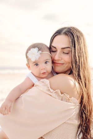 Soft peachy tones highlight intimate family moments on beach.