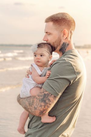 Sunset beach portrait with baby in white romper.