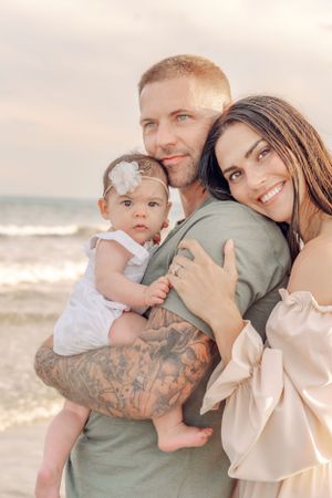 A tender family moment captured at sunset on the beach with warm golden light.