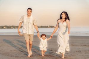 Family walking along shoreline during golden hour at the beach.