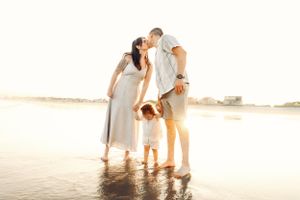 Family sharing intimate moments together on a beach during sunset.