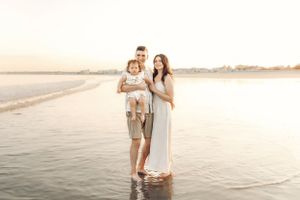 Family enjoying quality time together on beach with ocean view at sunset.